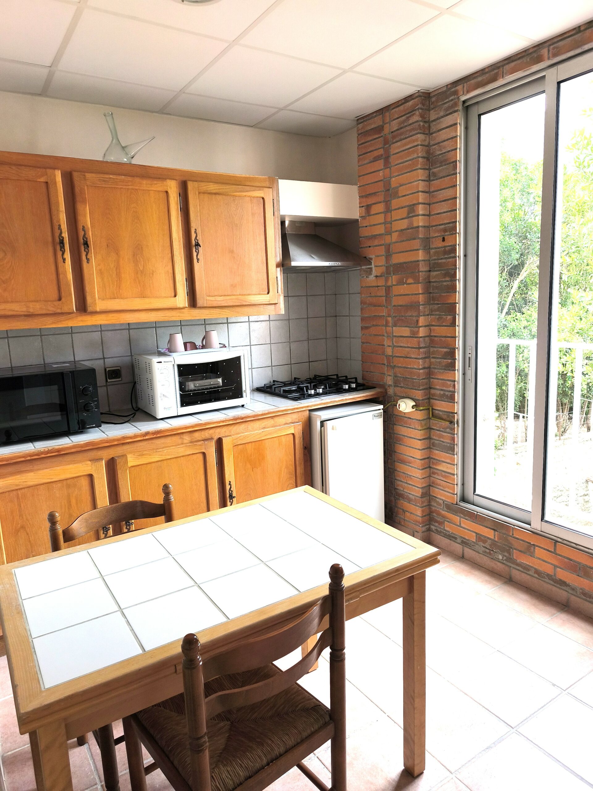 Photo montrant une cuisine d'un appartement avec une chambre sur la page appartements de l'hôtel la pergola